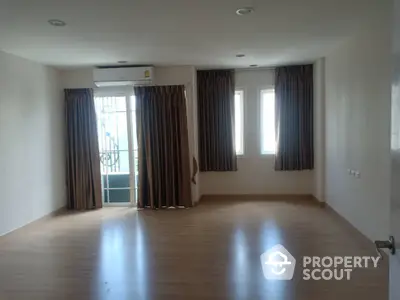 Spacious empty room with wooden flooring and large windows