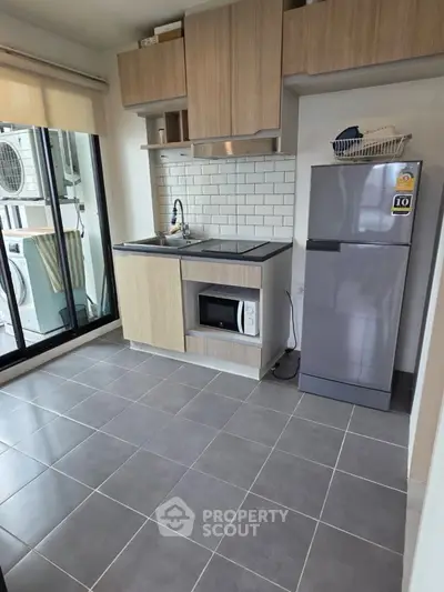 Modern kitchen with sleek appliances and open layout, featuring a fridge and microwave.