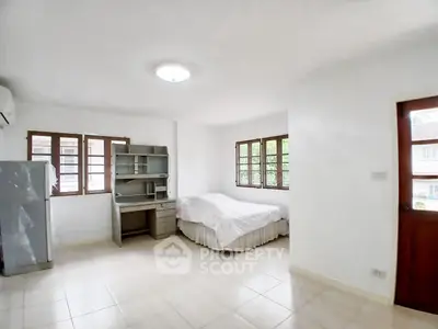 Spacious bedroom with natural light and modern furnishings in a cozy apartment.