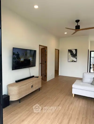 Modern living room with sleek TV setup and stylish ceiling fan
