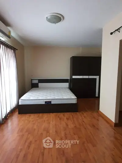 Spacious bedroom with wooden flooring and modern furniture in a cozy apartment.