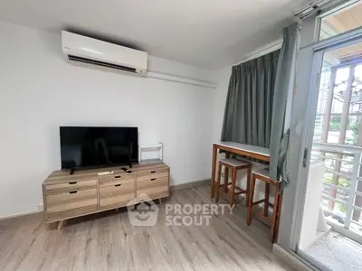 Modern living room with air conditioning and balcony access, featuring stylish furniture and natural light.