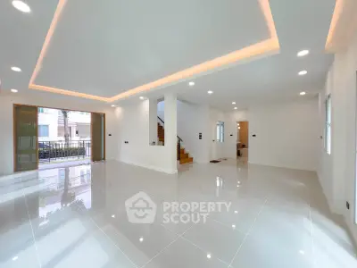 Spacious modern living room with glossy tiled floors and recessed lighting, open layout with staircase.