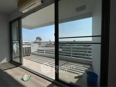Spacious balcony with city view and sliding glass doors in modern apartment.