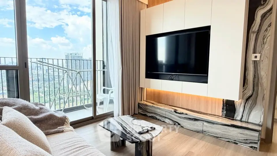 Modern living room with balcony view, featuring sleek TV setup and stylish decor.