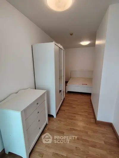 Cozy bedroom with wooden flooring and white furniture, perfect for a minimalist lifestyle.