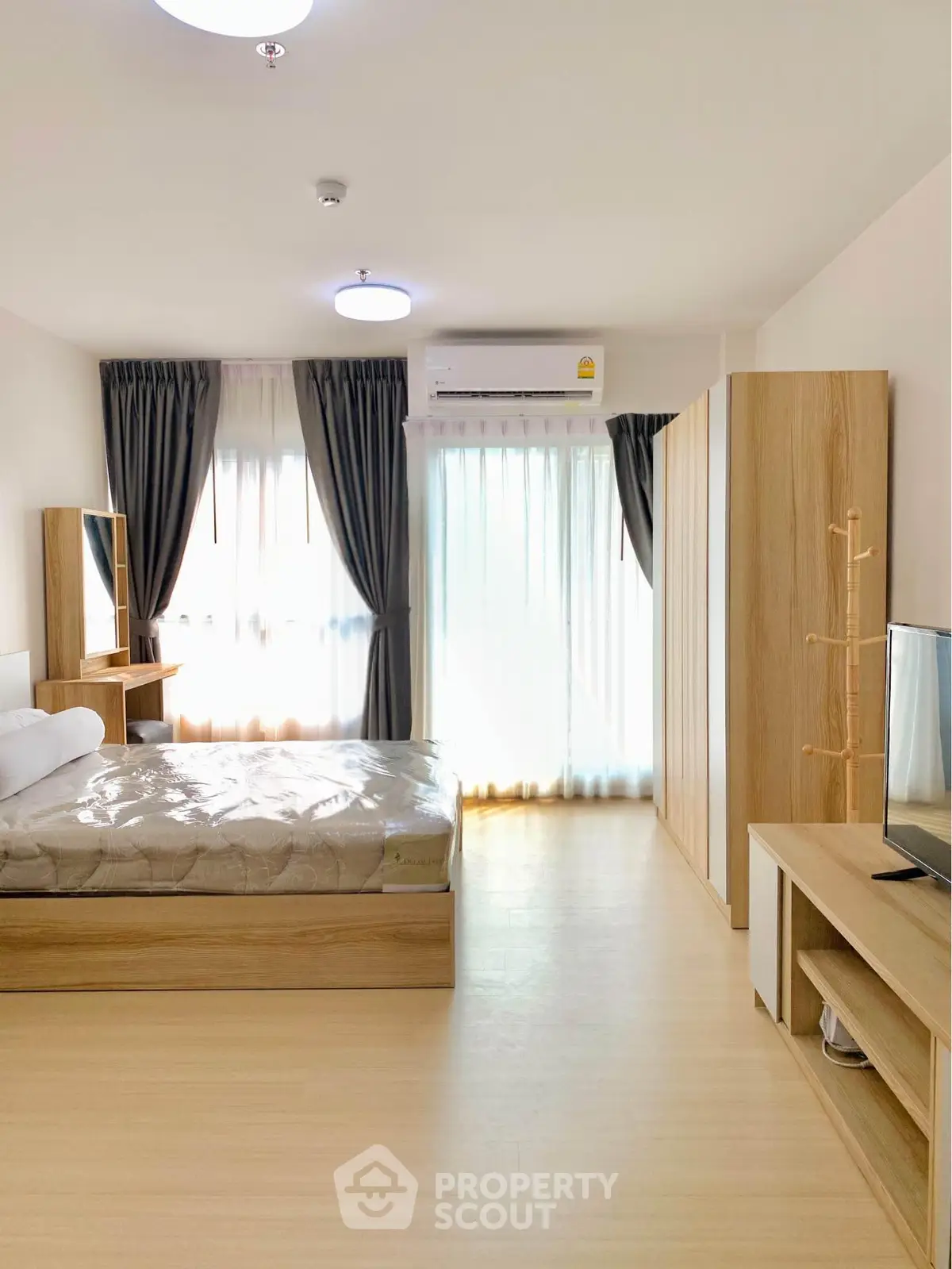 Spacious modern bedroom with natural light and stylish wooden furniture