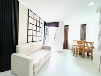 Bright modern living room with white sofa and dining area, featuring large windows and elegant decor.