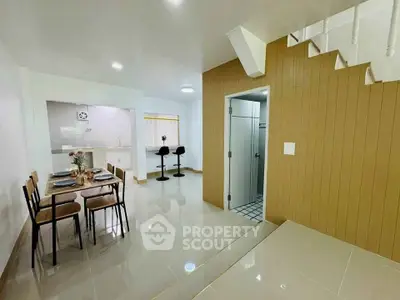 Modern open-plan dining area with sleek kitchen and stylish staircase