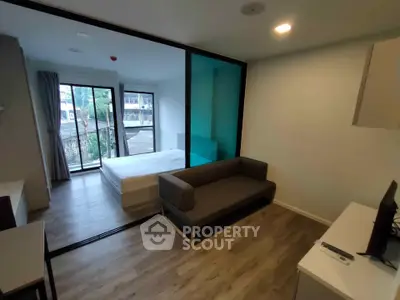 Modern studio apartment with glass partition, cozy living area, and balcony view.
