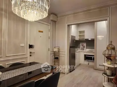 Elegant dining area with chandelier and modern kitchen in open layout apartment.