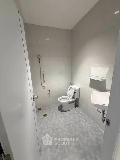 Modern bathroom with tiled walls, toilet, and sink in a minimalist design.
