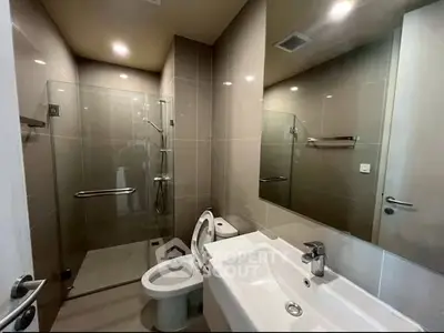 Modern bathroom with glass shower and sleek fixtures in a contemporary apartment.