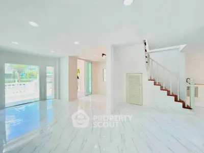 Spacious modern living room with marble flooring and staircase in bright open layout.