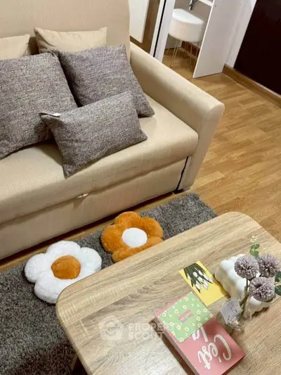 Cozy living room with beige sofa, decorative pillows, and wooden coffee table.