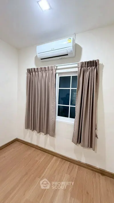 Cozy bedroom with wooden flooring and air conditioning, perfect for comfortable living.