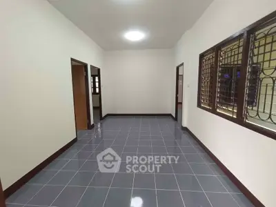 Spacious interior room with tiled flooring and large windows, ideal for versatile use.