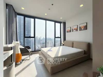 Modern bedroom with large windows offering stunning city views and stylish decor.