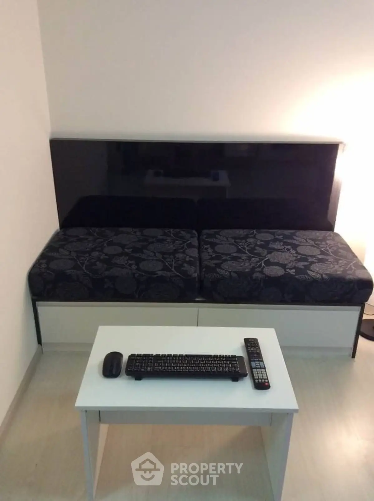 Modern minimalist living room with sleek black sofa and compact white table.