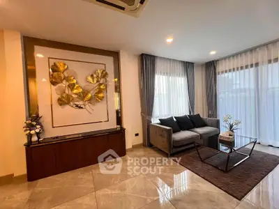 Elegant living room with modern decor and large windows, featuring a stylish sofa and artistic wall piece.