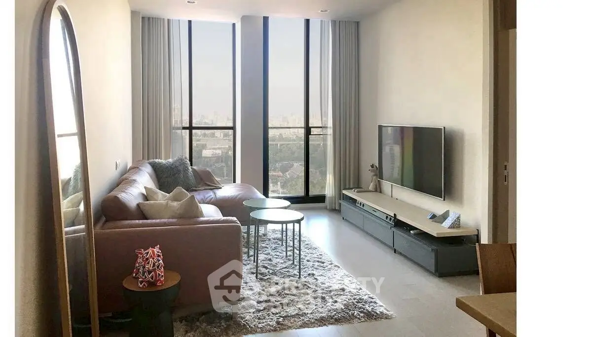 Modern living room with large windows and city view, featuring stylish furniture and decor.