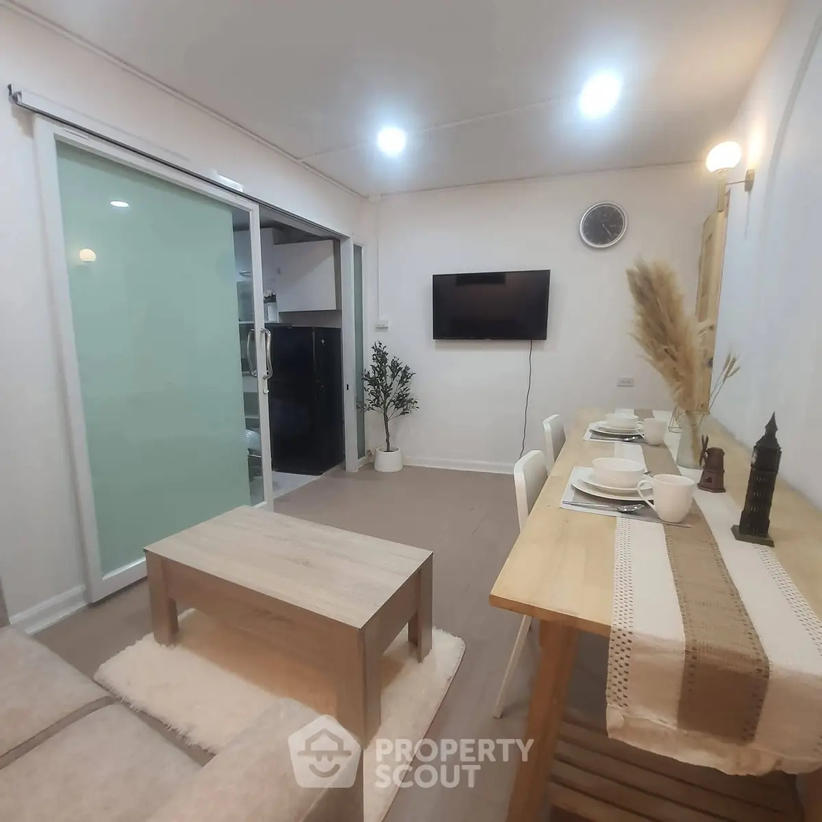 Modern living room with dining area and wall-mounted TV in cozy apartment