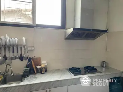 Modern kitchen with marble countertop and gas stove, featuring sleek design and ample natural light.