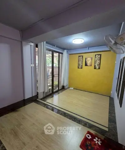 Charming living room with wooden flooring and large window overlooking garden.