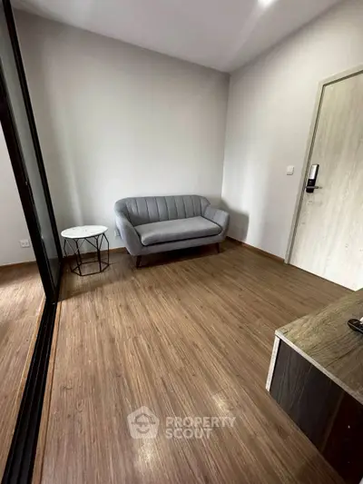 Modern minimalist living room with sleek gray sofa and wooden flooring