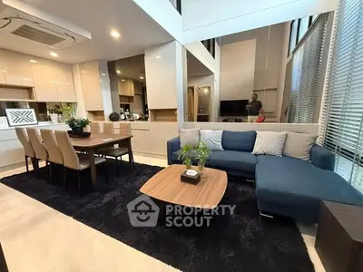 Modern living room with open kitchen, stylish furniture, and large windows for natural light.