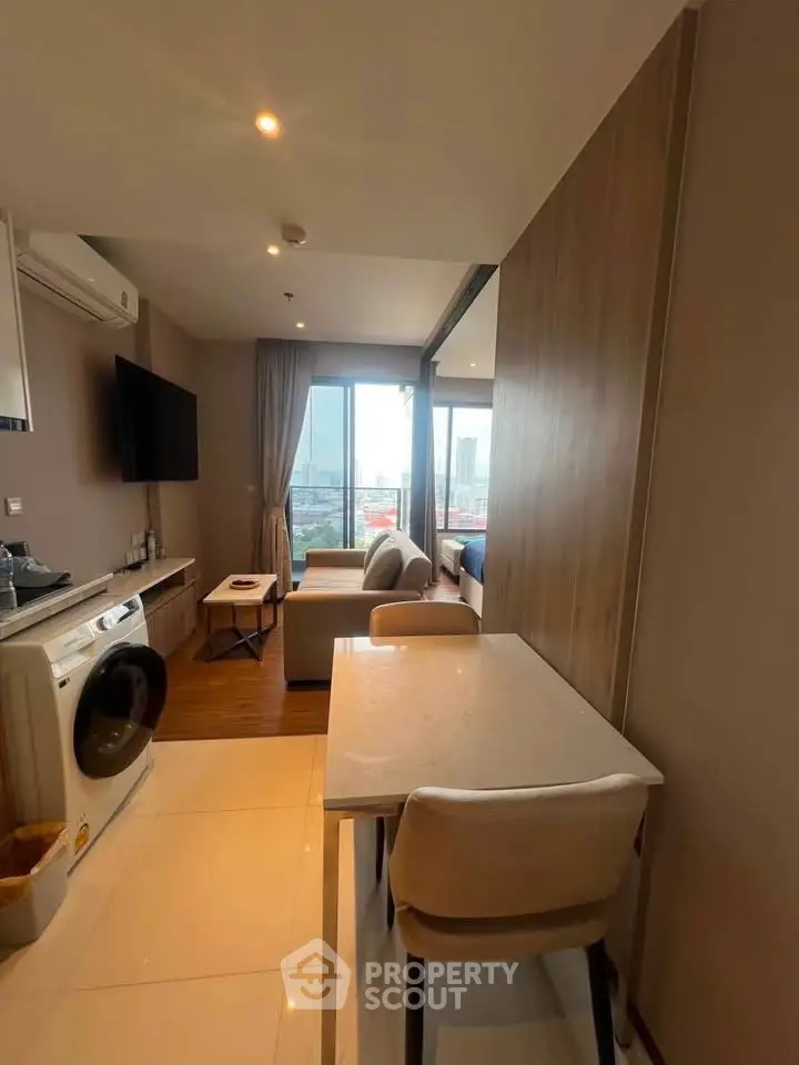 Modern apartment interior with open layout, featuring a cozy living area and a washing machine.