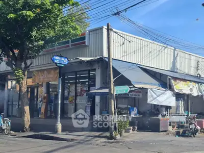Street view of a corner convenience store with outdoor seating area.