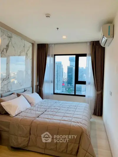 Modern bedroom with city view, featuring elegant decor and large window for natural light.