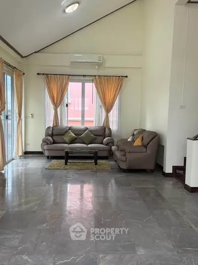 Spacious living room with elegant marble flooring and cozy seating area, perfect for relaxation.