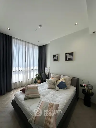 Modern bedroom with stylish decor and large window, featuring cozy bed and elegant furnishings.