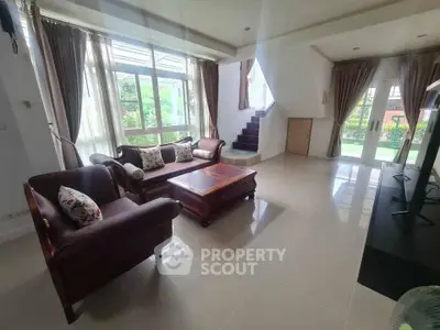 Spacious living room with elegant furniture and large windows offering garden views.