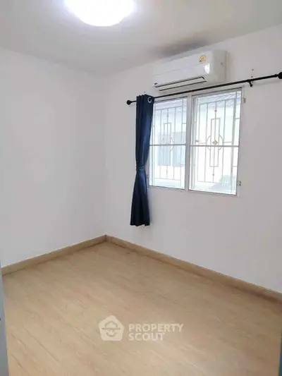 Bright empty room with wooden flooring and air conditioning, ideal for customization.