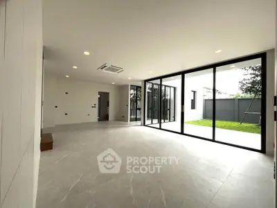Spacious modern living room with large glass doors opening to a lush garden, perfect for natural light lovers.