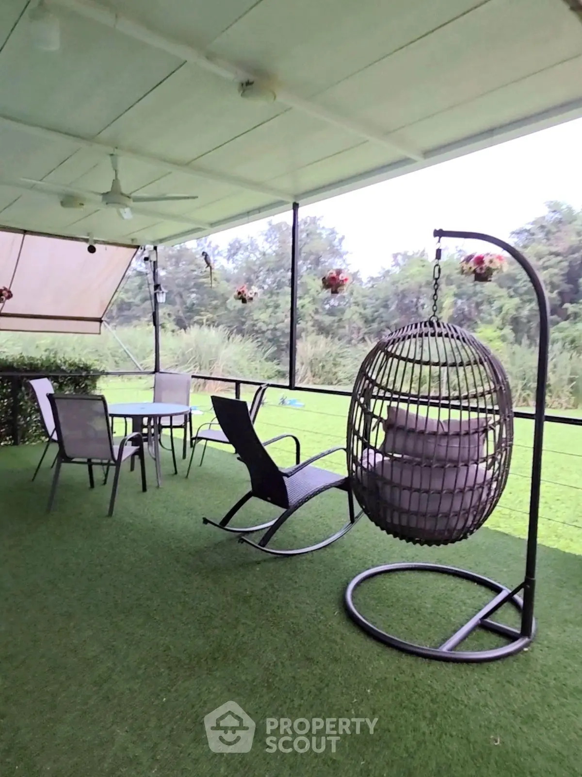 Spacious balcony with modern outdoor furniture and lush green view.