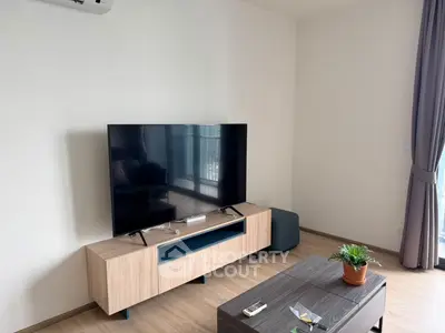 Modern living room with large TV and stylish furniture, featuring a cozy atmosphere and natural light.