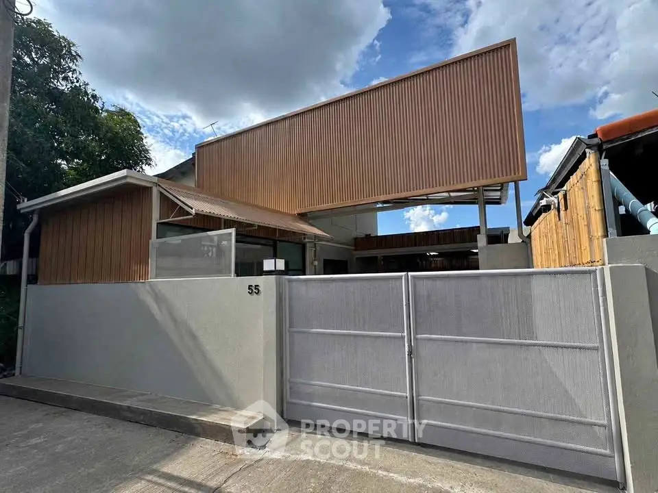 Modern architectural home with sleek facade and gated entrance under a clear blue sky.