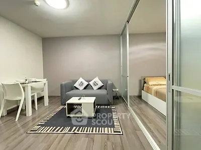 Modern living room with cozy sofa and dining area, adjacent to a stylish bedroom.