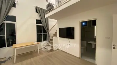 Modern loft-style living room with high ceilings and mezzanine, featuring large windows and minimalist decor.