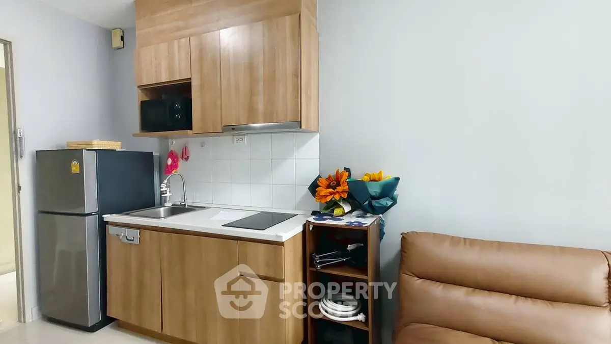Modern compact kitchen with wooden cabinets and sleek appliances in cozy apartment.