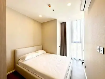 Modern bedroom with natural light and minimalist design in a high-rise apartment.