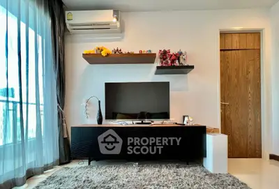 Modern living room with stylish TV stand, plush rug, and decorative shelves in a bright apartment.