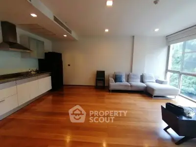Spacious modern living room with open kitchen and large windows offering natural light.