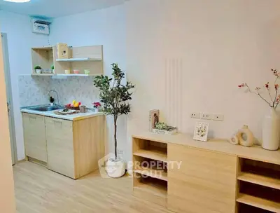 Modern kitchen with light wood cabinets and open shelving in a cozy apartment.