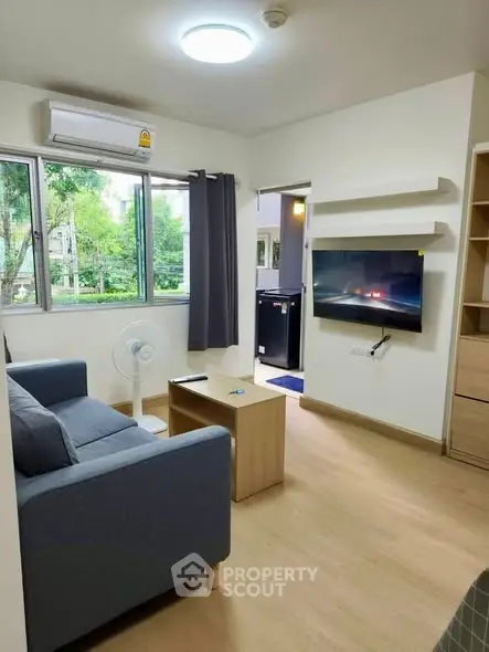 Modern living room with sofa, wall-mounted TV, and large window view.