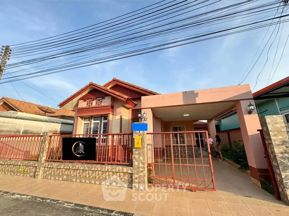 Charming single-story house with red roof and gated entrance in a serene neighborhood.